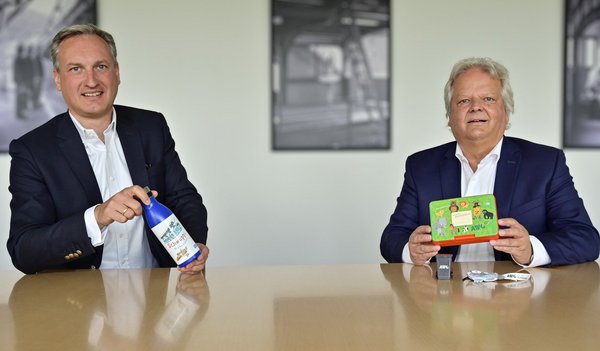WSW-Vorstandschef Markus Hilkenbach (links) und AWG-Geschäftsführer Martin Bickenbach (rechts zeigen die Trinkflasche und die Brotdosen für die Wuppertaler Erstklässler. 